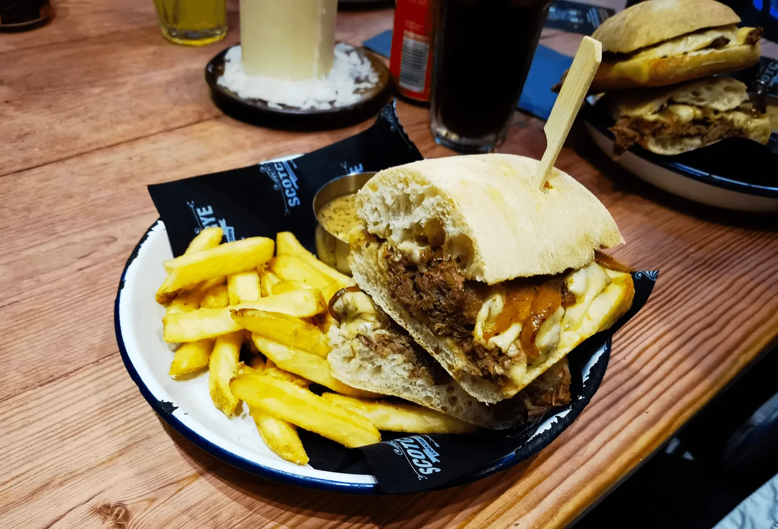 Scotch & Rye 餐桌上的 brisket cheese steak 与薯条