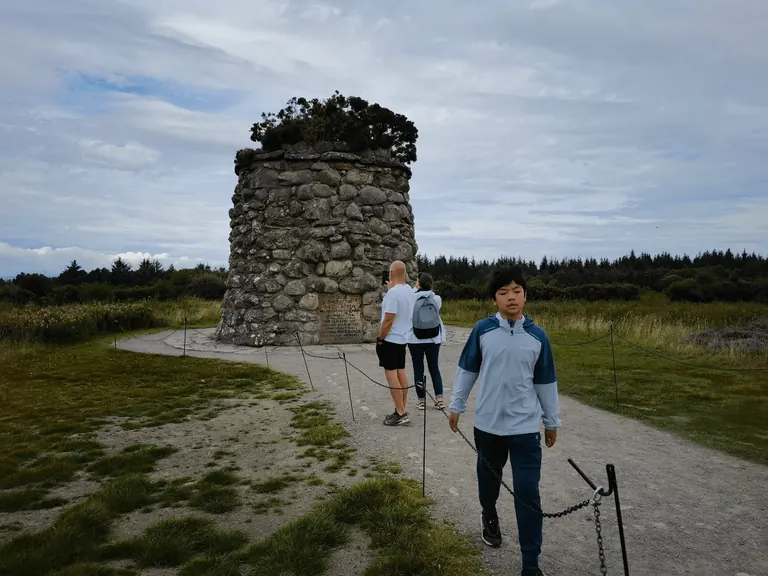 Feynman 走近 Culloden 石砌纪念塔,周围游客停留。