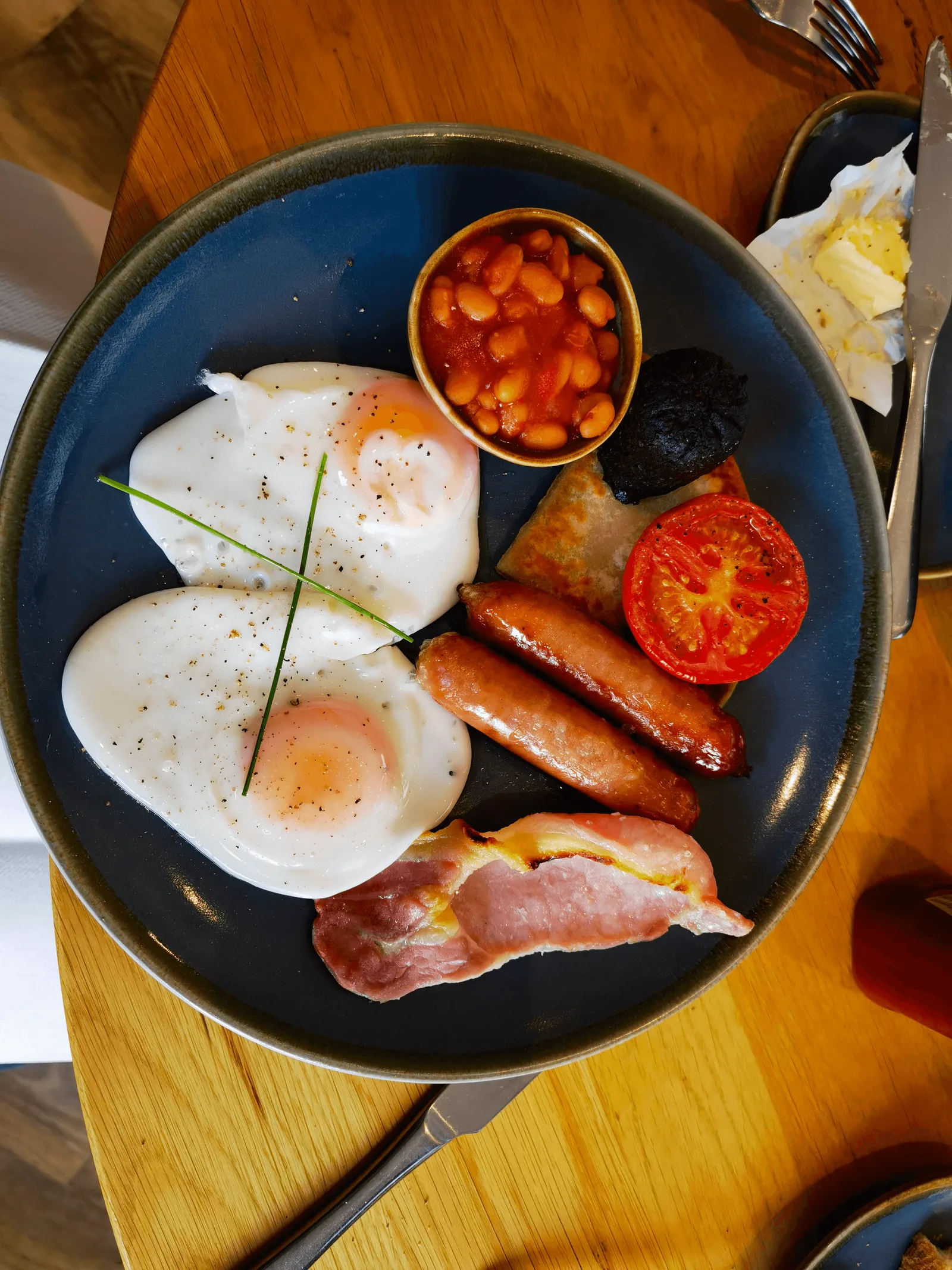 俯拍苏格兰早餐:双煎蛋、香肠、培根、黑布丁、烤番茄、薯饼与 baked beans