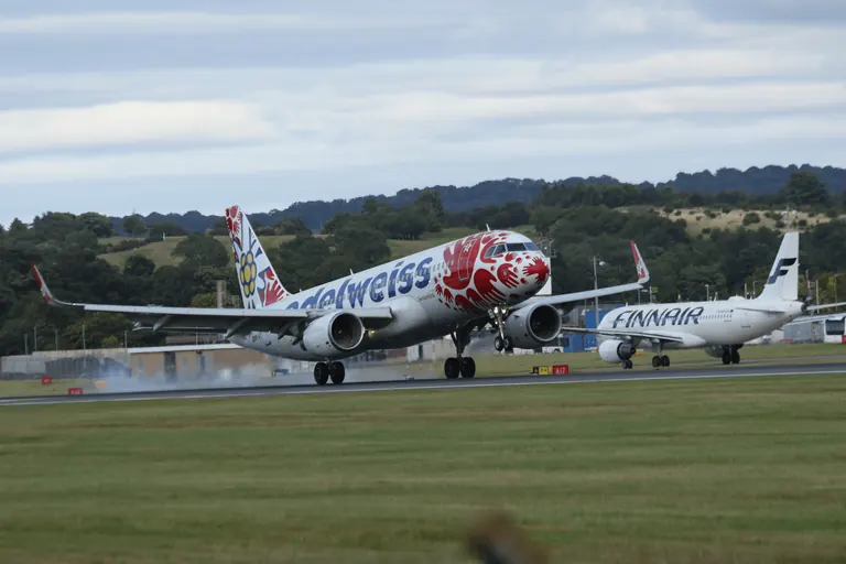 Edelweiss Air 客机触地或离地扬起轻烟,后方是 Finnair 客机。