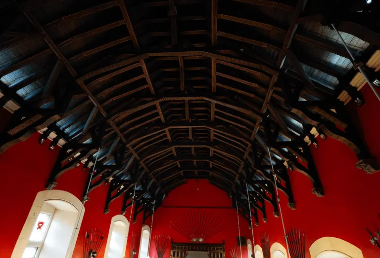Great Hall 内从入口仰望的木构屋顶与红色墙面。