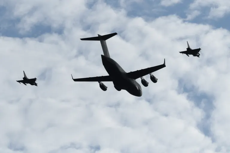 C-17 与两架 Typhoon 低空编队从云层下飞过。