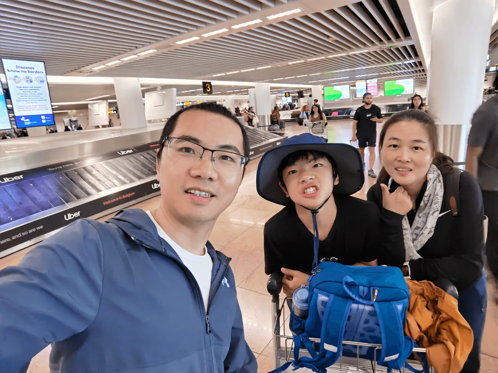 机场大厅内带着手提行李箱的家庭自拍合影。