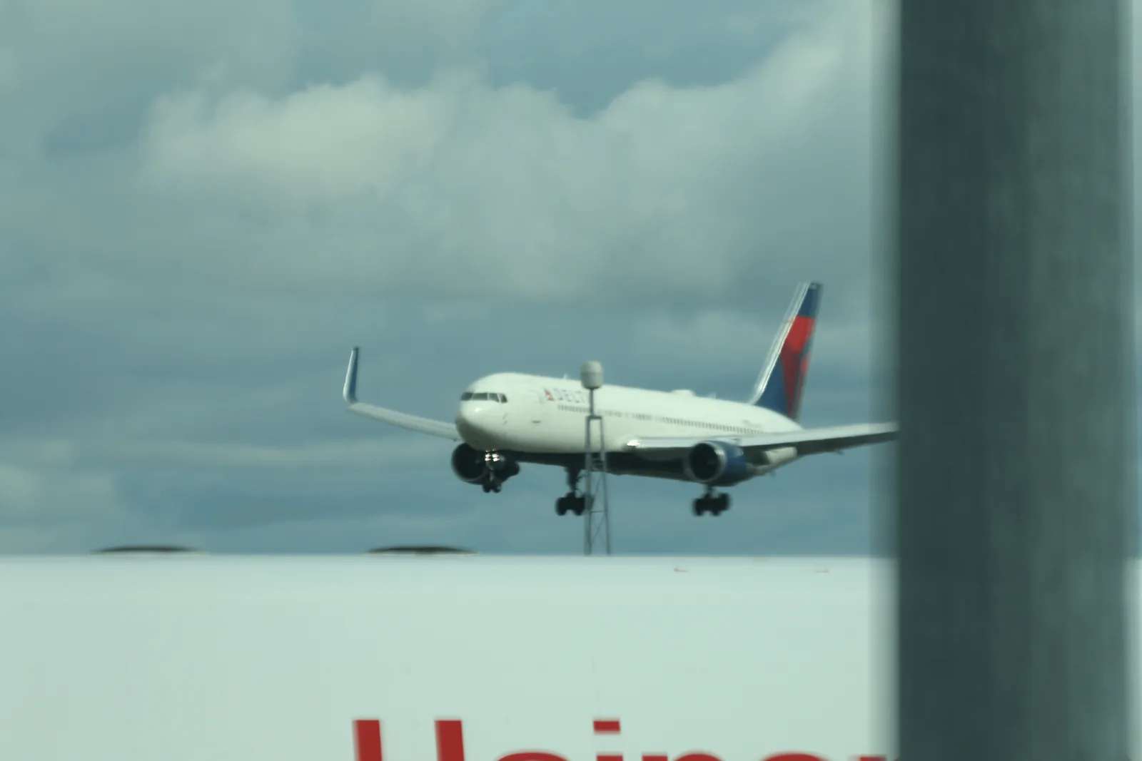 Delta 涂装客机起落架放下，从航站楼前方进近